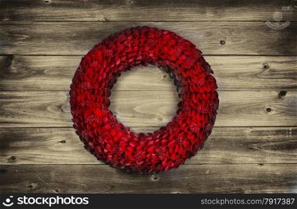 Vintage concept of a wooden petal red holiday wreath on rustic wood