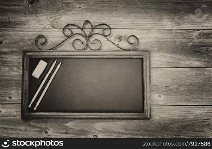 Vintage concept of an old fashion chalkboard, pencils and eraser on rustic wood. Layout in horizontal format.