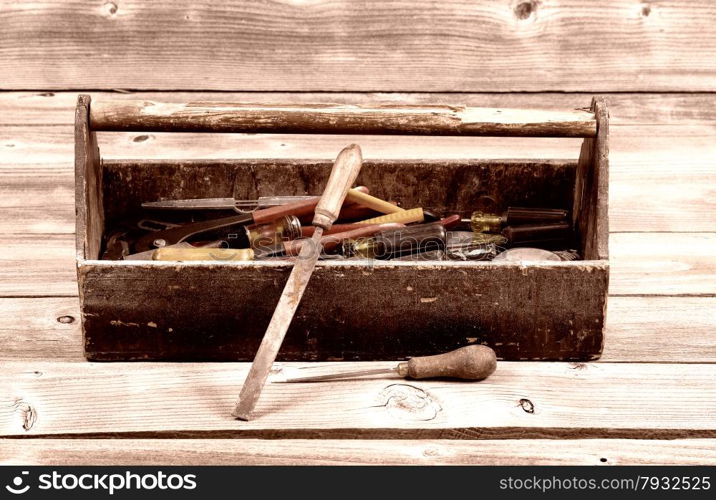Vintage concept of an old tool box filled with tools on rustic wooden boards