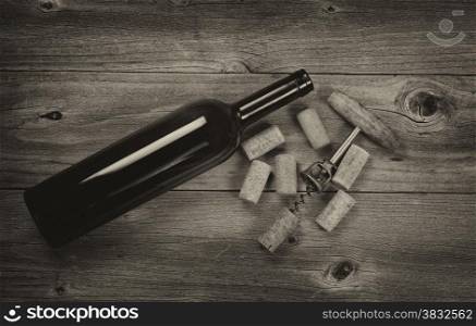 Vintage concept of antique corkscrew, used corks, and wine bottle on rustic wooden boards. Top view angled shot in horizontal format with vignette border.