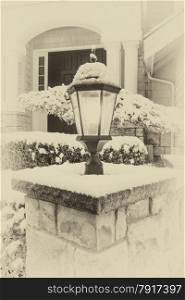 Vintage concept of lamp post, with snow on top, in front of home