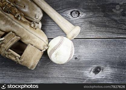 Vintage concept of old worn glove, bat and used baseball on rustic wood
