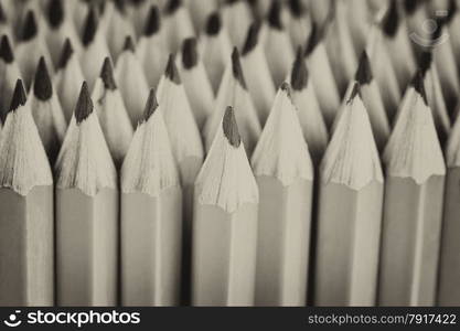 Vintage concept of stacked pencils with focus on tip of centered pencil with filled frame.