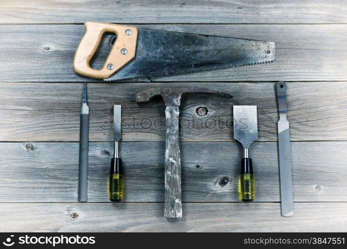 Vintage concept of used tools on rustic wooden boards consisting of hammer, metal files, hand saw, and chisels.