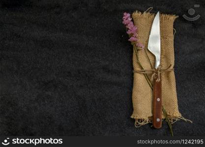 Vintage cutlery knife and flower on black background. Top view, Copy space, Selective focus.