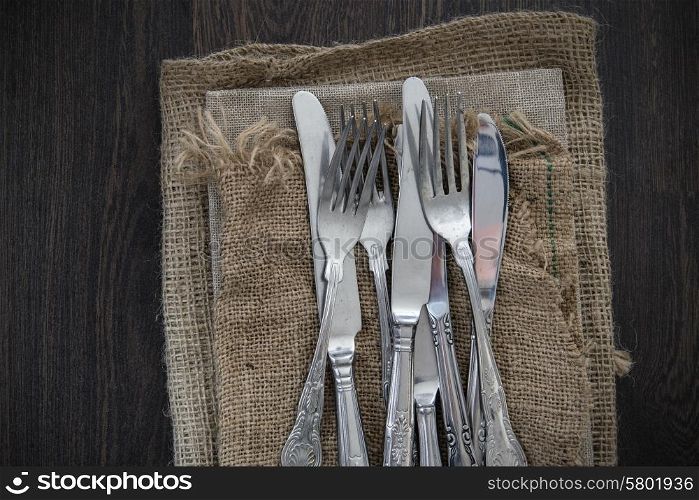 Vintage cutlery on hessian cloths on wooden background