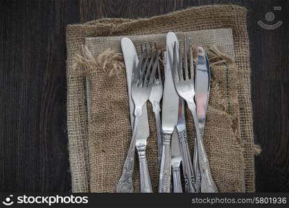 Vintage cutlery on hessian cloths on wooden background