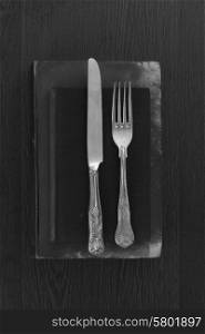 Vintage cutlery on old books in black and white