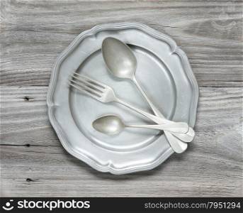 Vintage cutlery on pewter plate on the background of old wooden planks