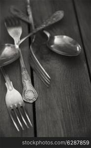 Vintage cutlery on rustic wooden table background, in black and white