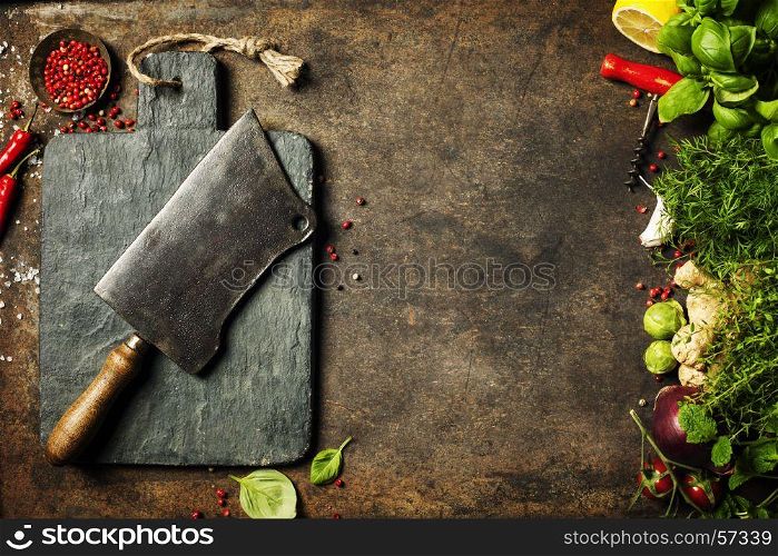 Vintage cutting board,meat cleaver and cooking ingredients on dark rustic background