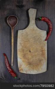 Vintage cutting board with red hot chili peppers and wooden spoon