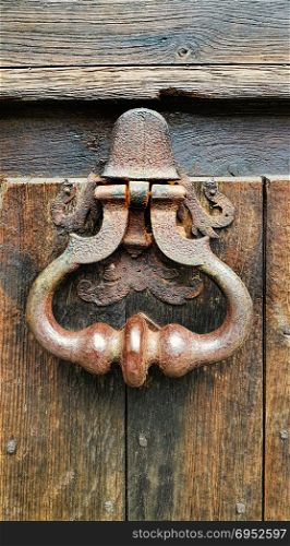 Vintage doorknocker close-up on weathered wooden door background, Troyes, France