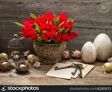 vintage easter decoration with cage, eggs and red tulip flowers. country style home interior