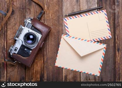Vintage envelope with post card and retro camera on old wooden table