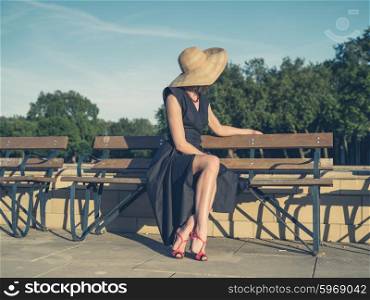 Vintage filtered shot of an elegant young woman in dress and high heels sitting on a park bench