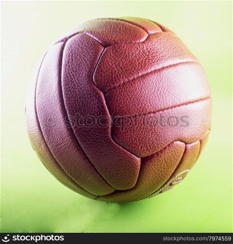 Vintage football (soccer ball) in leather over green background, square image