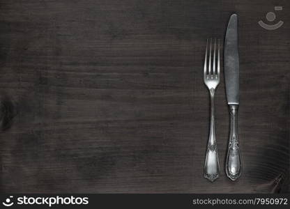 Vintage fork and knife on old wooden board