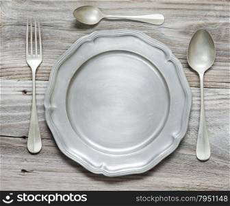 Vintage fork, spoons and pewter plate on old wooden boards