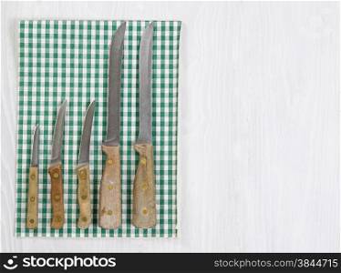 Vintage full knife set with striped cloth napkin on white wood. Format in horizontal layout.
