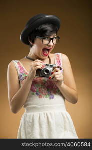 Vintage girl taking pictures using an old camera in a beige background