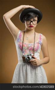 Vintage girl taking pictures using an old camera in a beige background