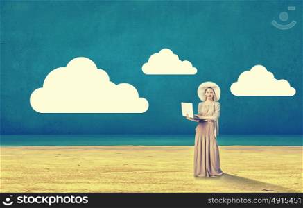 Vintage girl with laptop. Young lady in hat and long dress using laptop