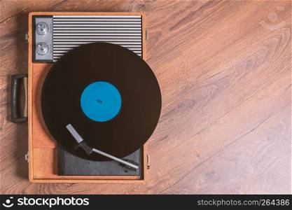 Vintage Gramophone with a vinyl record on wooden table, top view and copy space,photo.