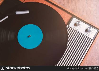 Vintage Gramophone with a vinyl record on wooden table, top view close up,vintage style.