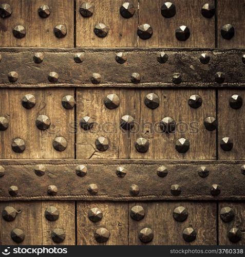 Vintage grunge wooden background door gate of the old castle detail with metal rivets. Square format