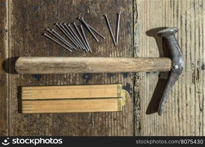 Vintage hammer, nails and wooden centimeter on plank