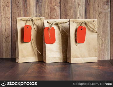 Vintage handmade gift boxes made of kraft paper on a wooden background in the Christmas style, decorated with golden Christmas balls, cones, fir branch. Christmas, New Year, winter holiday. Kraft package, holiday concept, top view, flat lay.. Vintage handmade gift boxes made of kraft paper on a wooden background in the Christmas style, decorated with golden Christmas balls, cones, fir branch.