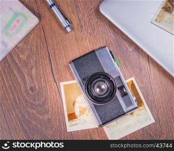 Vintage image with old Camera,old photo,laptop,pen and passport on wood table from above.