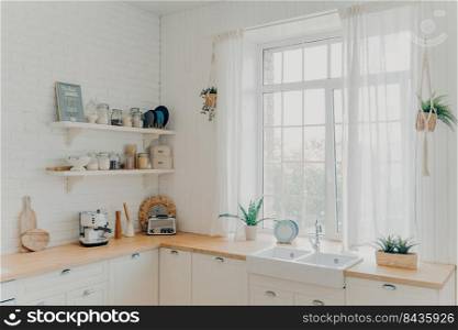 Vintage interior. Domestic family kitchen. Brightly lit scandinavian kitchen interior with window. Wooden counters and cabinet along brick walls. Concept of modern apartment, mortgage and renovation.. Domestic family kitchen. Brightly lit scandinavian kitchen interior with window. Modern apartment.