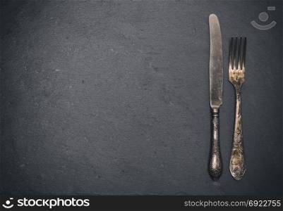 vintage iron fork and knife on a black background, empty space