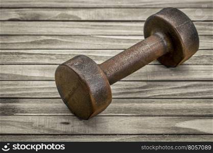 vintage iron rusty dumbbell on wood planks background - fitness concept