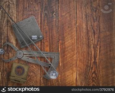 vintage jeweler tools and diamonds over wooden bench, space for text