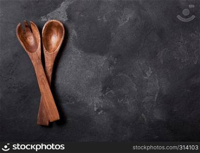 Vintage kitchen wooden utensils on black stone table background. Top view. Space for text.
