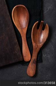 Vintage kitchen wooden utensils over black cloth on stone table background. Top view.