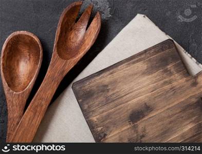 Vintage kitchen wooden utensils with chopping board on black stone table background. Top view. Space for text.