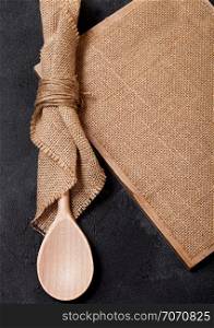 Vintage kitchen wooden utensils with linen board on stone table background. Top view.