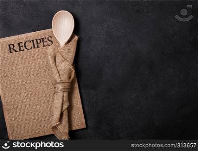 Vintage kitchen wooden utensils with linen recipes board on stone table background. Top view.