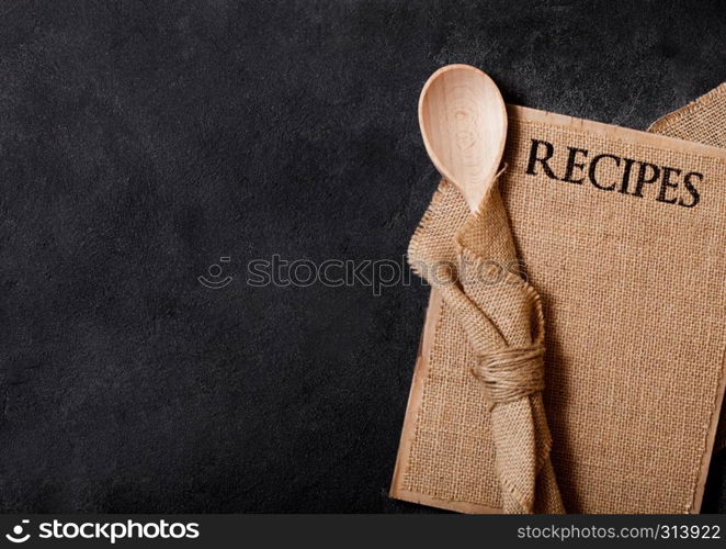 Vintage kitchen wooden utensils with linen recipes board on stone table background. Top view.