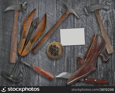 vintage ladies shoe and shoemakers tools over wooden table, space for your text on a blank business card