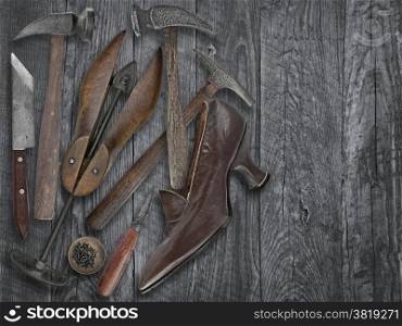 vintage ladies shoe and shoemakers tools over wooden table, space for your text
