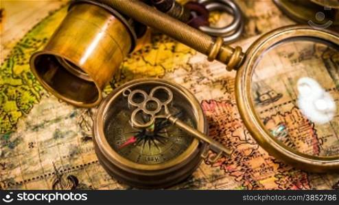 Vintage magnifying glass, compass, telescope and a pocket watch lying on ancient world map in 1565.