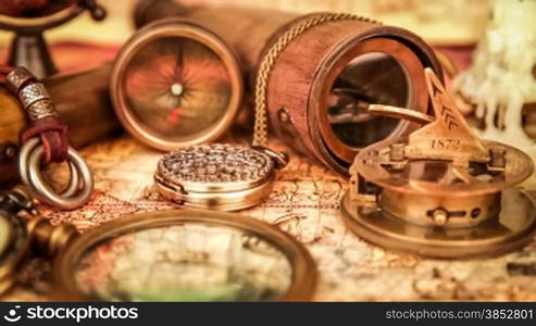 Vintage magnifying glass, compass, telescope and a pocket watch lying on ancient world map in 1565.