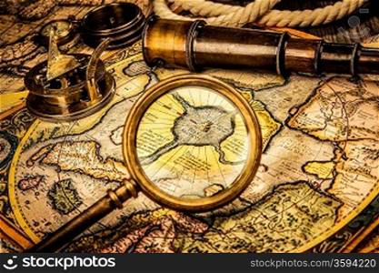 Vintage magnifying glass, compass, telescope lies on the ancient map of the North Pole (also Hyperborea). Arctic continent on the Gerardus Mercator map of 1595.