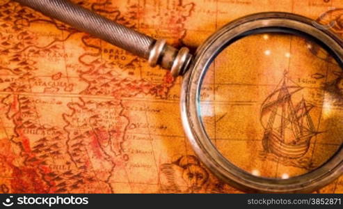 Vintage magnifying glass lying on ancient world map in 1565.