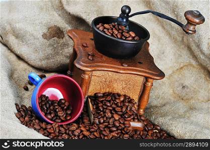 Vintage manual coffee grinder with coffee beans and cup